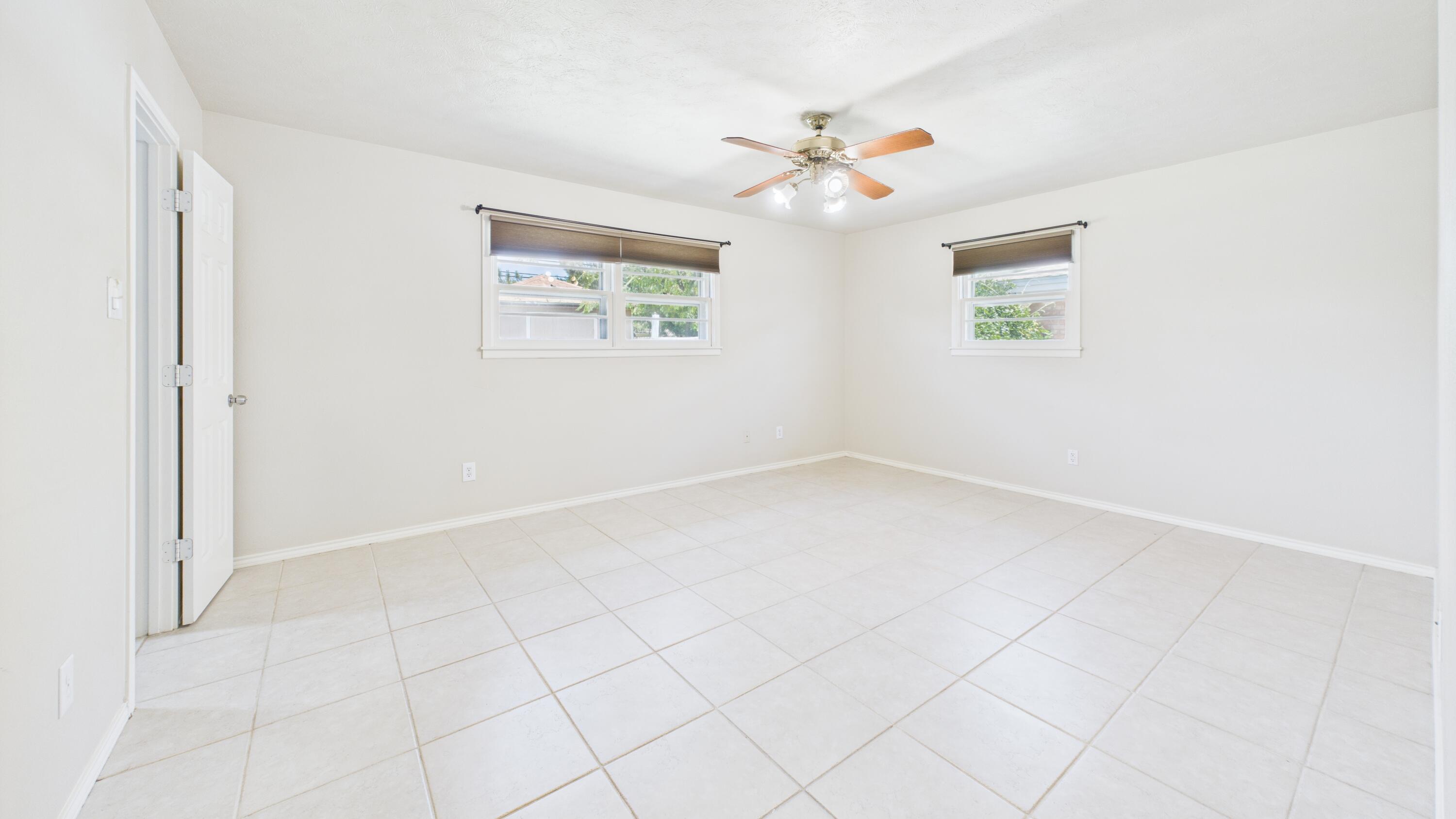 3022 67th Street Lubbock, TX 79413 - Photo 27 of 42 an empty room with a chandelier fan and windows