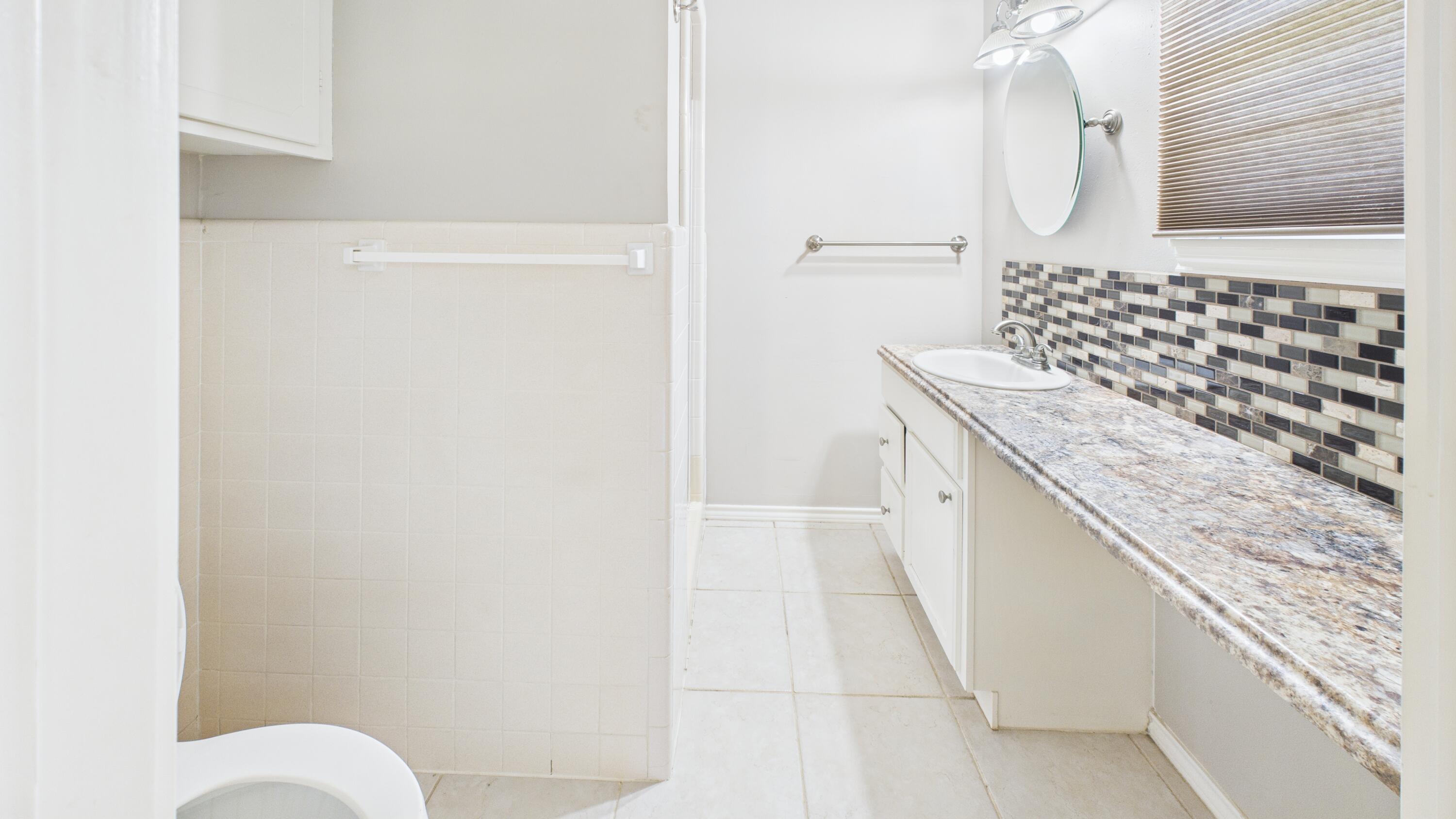 3022 67th Street Lubbock, TX 79413 - Photo 29 of 42 a bathroom with a granite countertop sink and a mirror