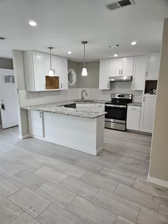 a large kitchen with stainless steel appliances granite countertop a stove top oven a sink a counter top space and cabinets