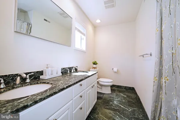a bathroom with a granite countertop sink and a toilet