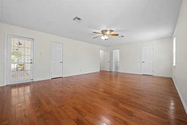 a view of empty room with wooden floor and fan