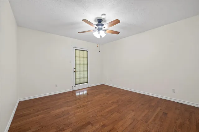 a view of an empty room with window and wooden floor