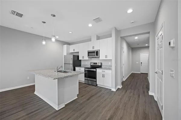 a kitchen with stainless steel appliances kitchen island wooden floors and white cabinets