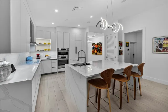 a kitchen with stainless steel appliances kitchen island granite countertop a sink and a refrigerator