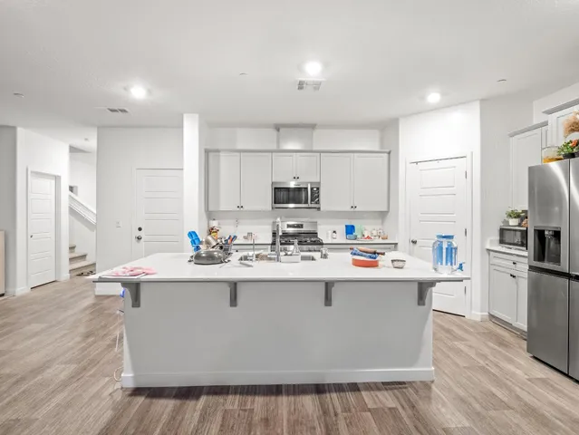 a view of kitchen with stainless steel appliances granite countertop a sink stove and refrigerator