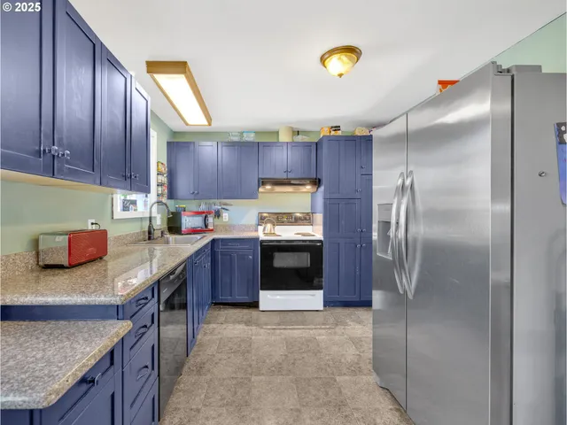 a kitchen with stainless steel appliances granite countertop a refrigerator a stove and a sink with wooden cabinets