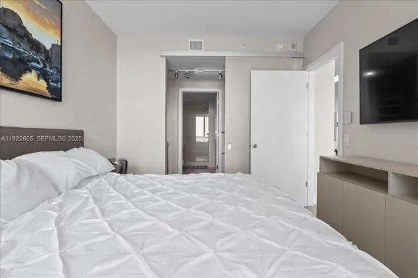 a bedroom with a bed a wall painting and a lamp on desk