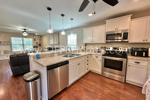 a kitchen with a refrigerator a sink and wooden floor