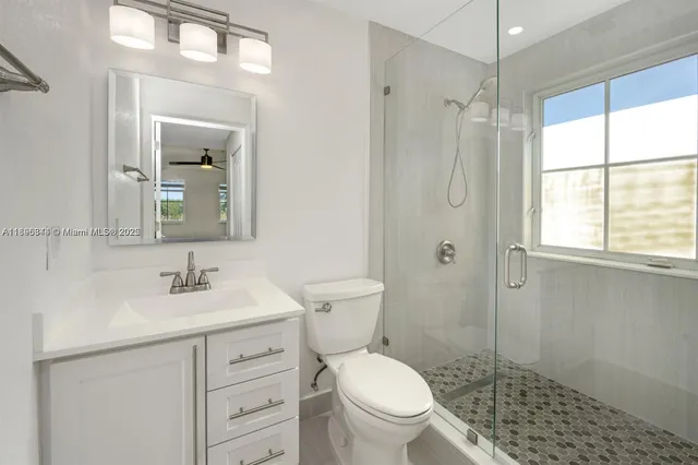 a bathroom with a toilet a sink a mirror a window and vanity