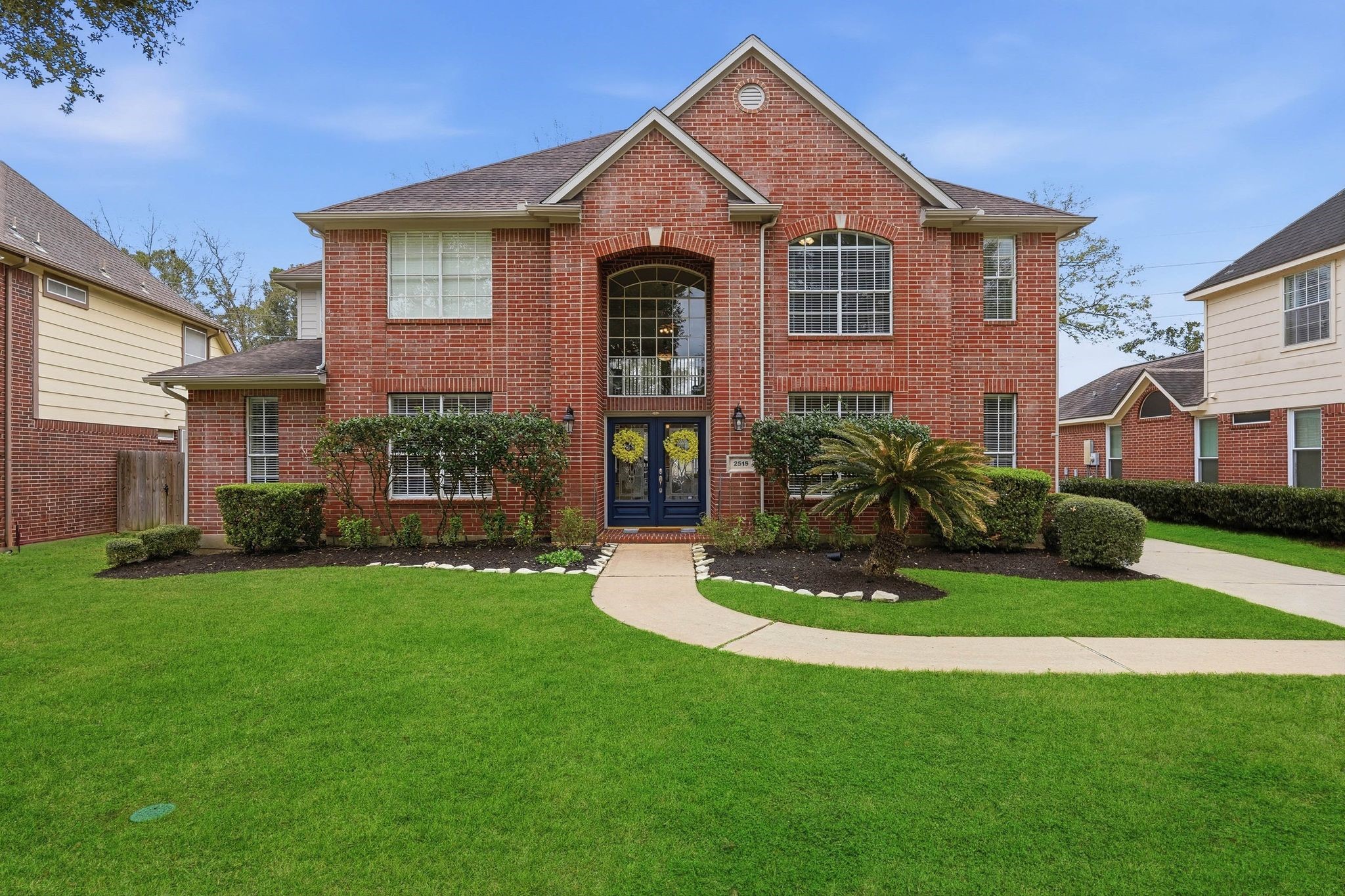 2515 Woodsboro Drive Spring, TX 77388 - Photo 44 of 44 This charming two-story home features a classic red brick exterior with large arched windows and a welcoming double-door entry. The well-maintained front yard is landscaped with shrubs and a palm, enhancing curb appeal.