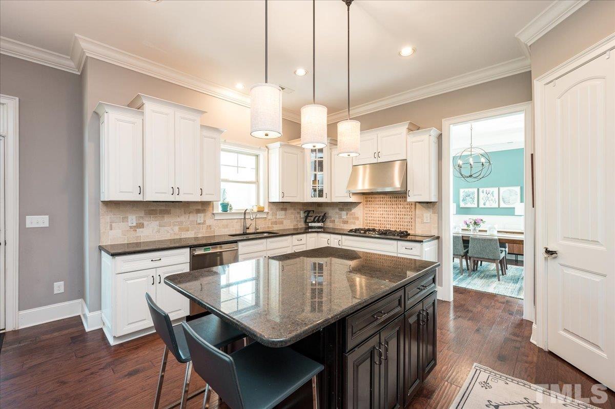 5100 Gansett Lane Raleigh, NC 27612 - Photo 5 of 39 a kitchen with a table chairs stove and cabinets