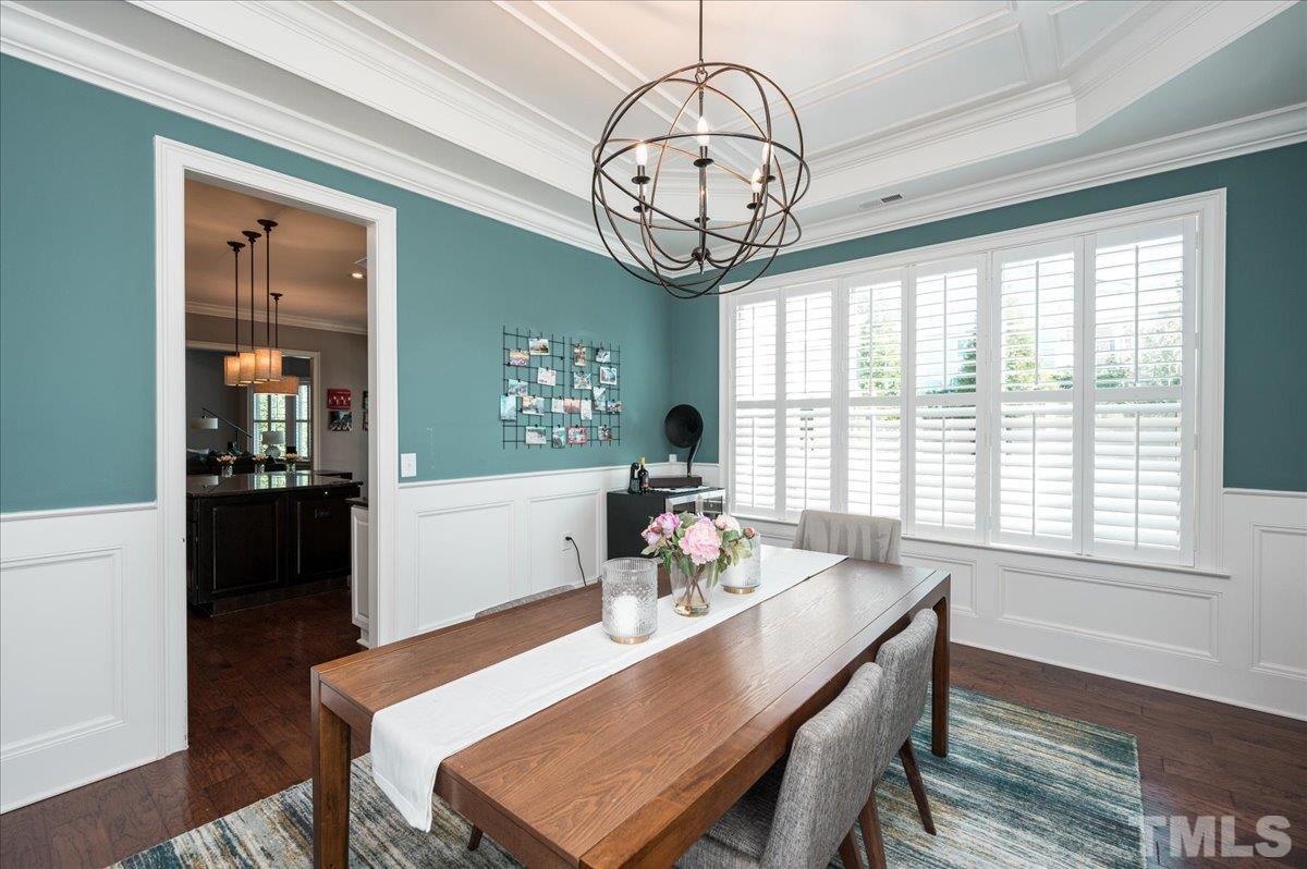 5100 Gansett Lane Raleigh, NC 27612 - Photo 8 of 39 a dining room with wooden floor a chandelier a wooden table and chairs