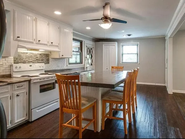 a kitchen with stainless steel appliances kitchen island granite countertop a dining table chairs and white cabinets