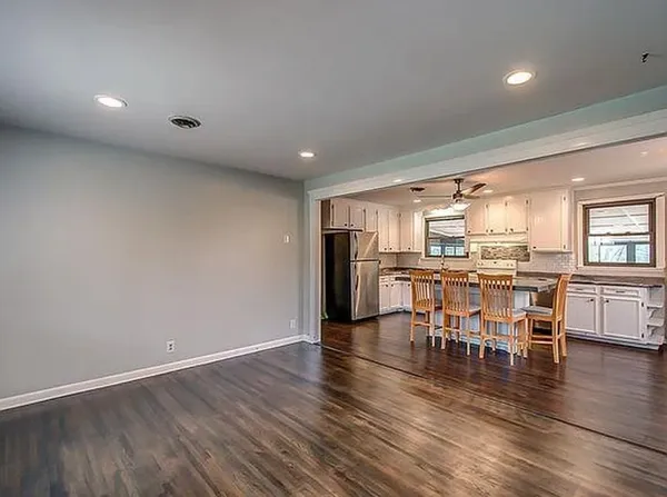 an open kitchen with wooden floor and stainless steel appliances