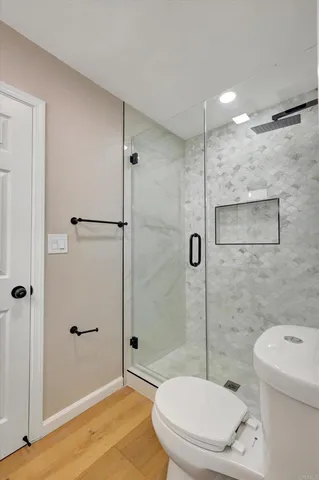a view of an empty room with wooden floor and a ceiling fan