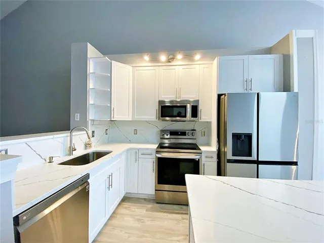 a kitchen with stainless steel appliances a refrigerator stove microwave and sink