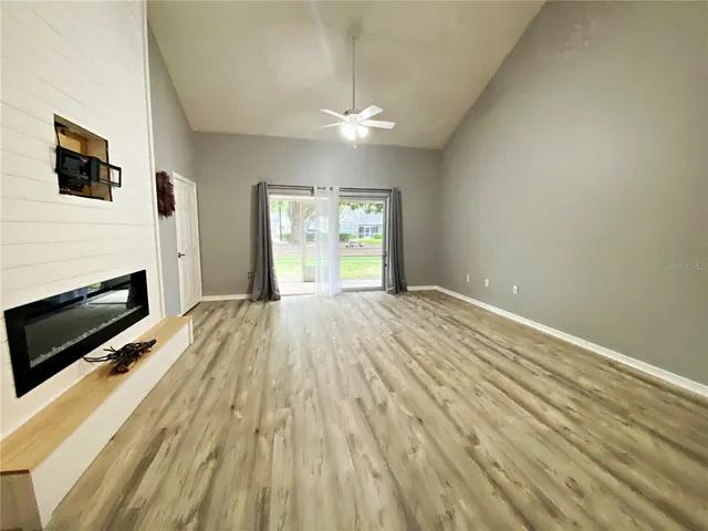 a view of empty room with wooden floor and fan