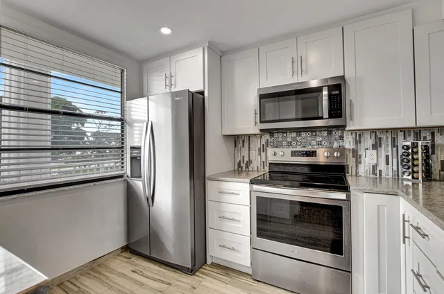 a kitchen with cabinets stainless steel appliances and a window