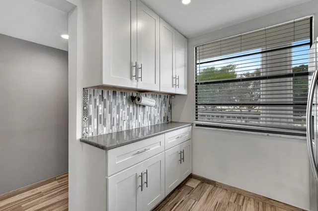 a kitchen with granite countertop white cabinets and stainless steel appliances