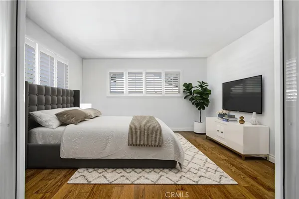 a bedroom with a bed television window and couch