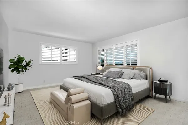 a bedroom with a bed a couch and potted plant