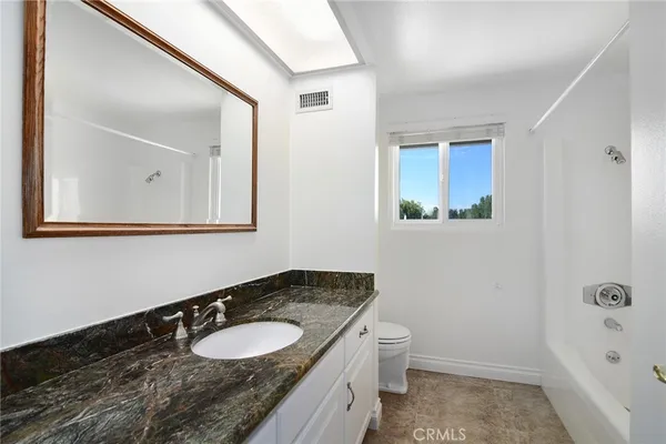 a bathroom with a granite countertop sink toilet and mirror