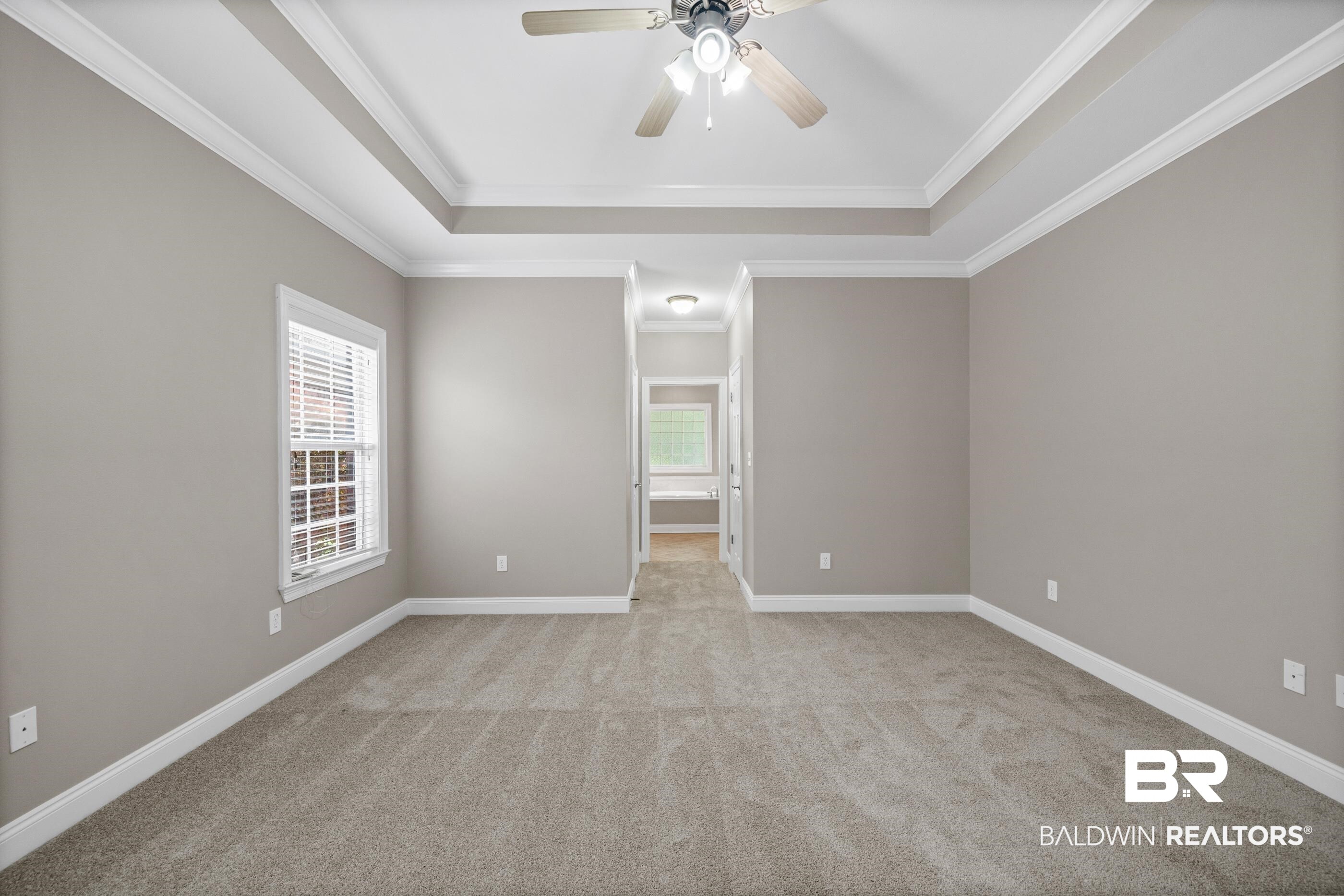 303 Savannah Circle Foley, AL 36535 - Photo 20 of 34 Spacious room featuring a tray ceiling with crown molding, a ceiling fan with light fixture, carpeted flooring, and a single window with blinds