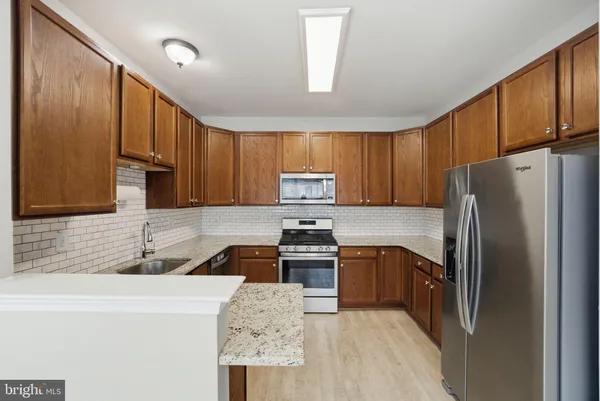a kitchen with granite countertop wooden cabinets a refrigerator and a sink