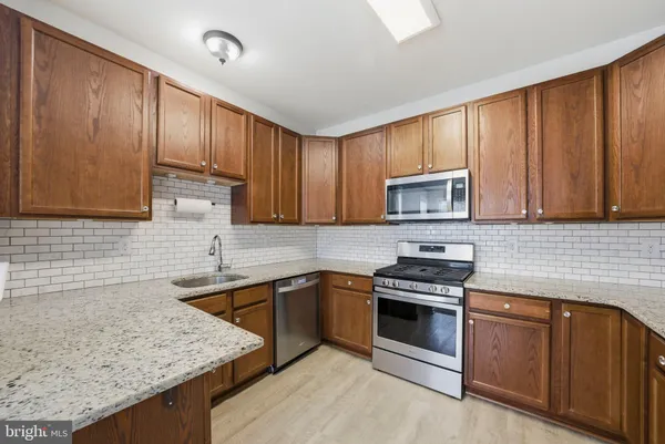 a kitchen with granite countertop stainless steel appliances and wooden cabinets