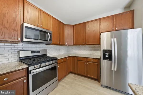 a kitchen with granite countertop a refrigerator stove and microwave