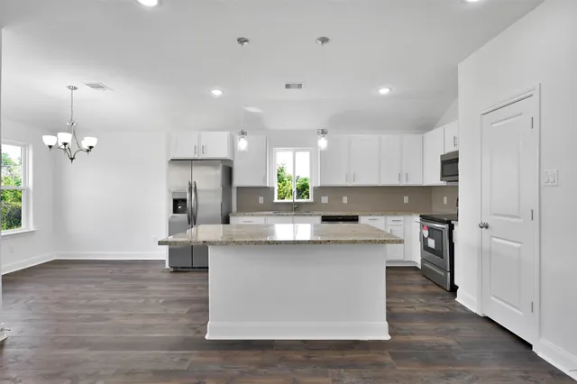 a kitchen with kitchen island a sink a stove a refrigerator and a window