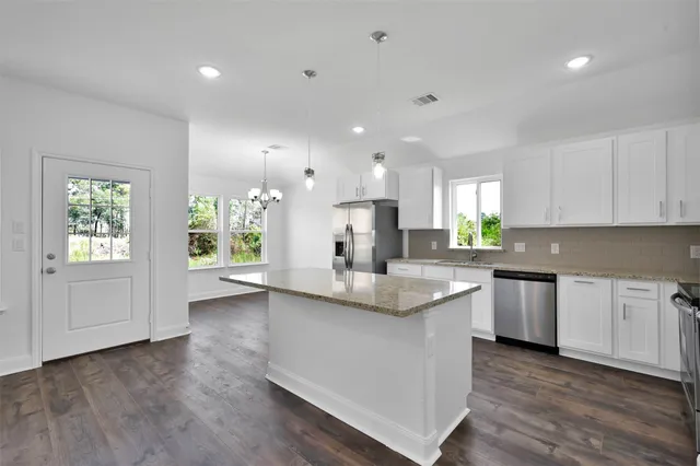 a kitchen with stainless steel appliances granite countertop a white cabinets and wooden floors