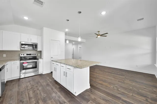 a kitchen with stainless steel appliances granite countertop a kitchen island hardwood floor and a sink