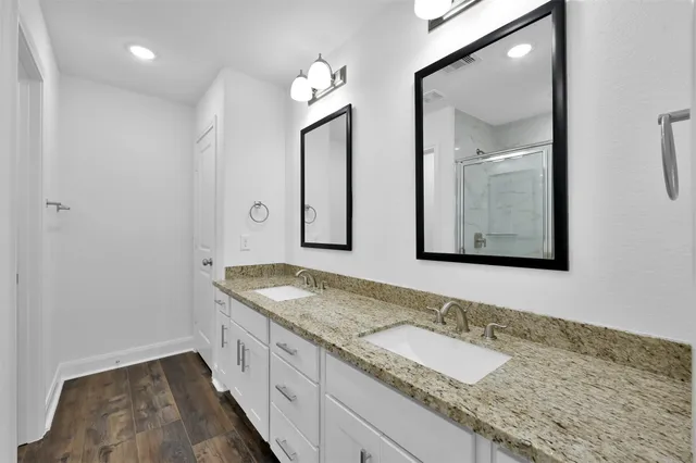 a bathroom with a granite countertop double vanity sink and a mirror