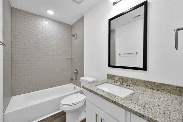 a bathroom with a granite countertop sink toilet and shower