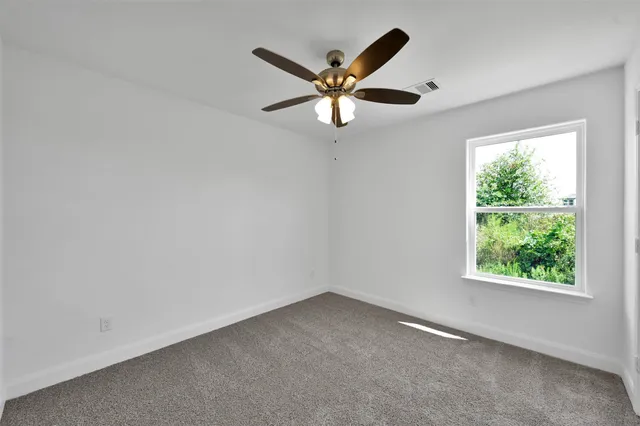 an empty room with a window and a fan