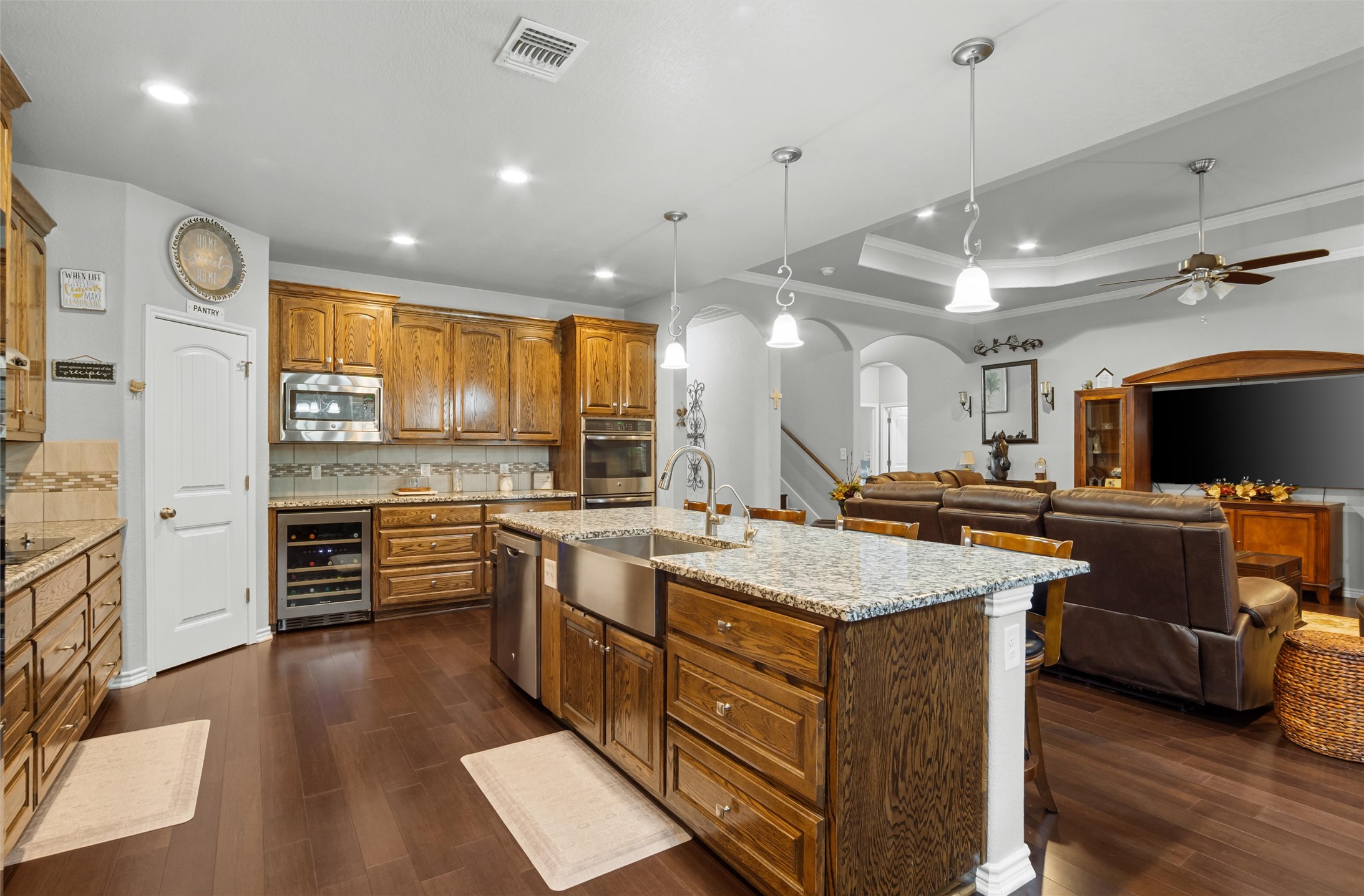 16017 Toby Court Temple, TX 76502 - Photo 11 of 33 Kitchen featuring arched walkways, decorative light fixtures, light stone counters, brown cabinets, and a kitchen island with sink