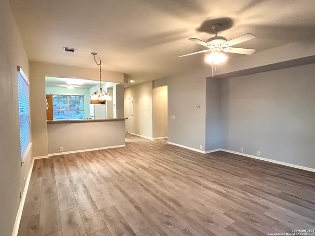 a view of empty room with wooden floor and fan