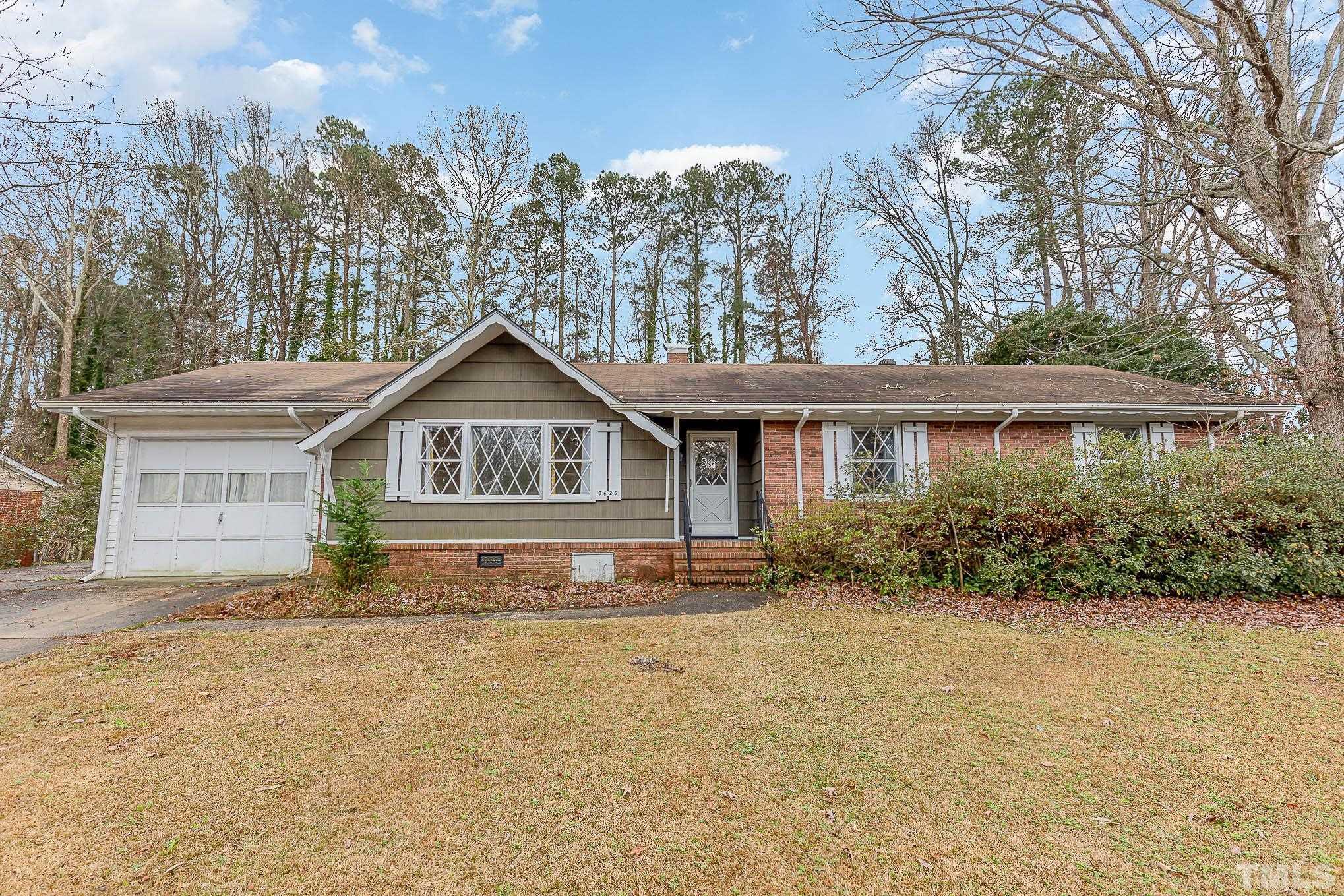 a front view of house with yard and trees in the background