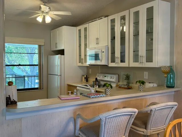 a kitchen with stainless steel appliances granite countertop a refrigerator a sink dishwasher a dining table and chairs with wooden floor