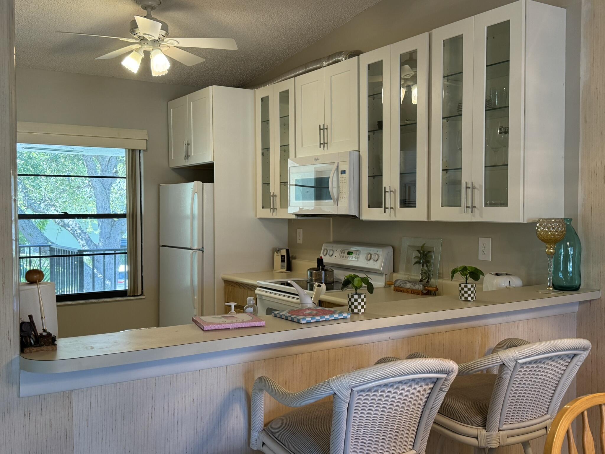 801 Sabal Ridge Circle, Unit H Palm Beach Gardens, FL 33418 - Photo 14 of 42 a kitchen with stainless steel appliances granite countertop a refrigerator a sink dishwasher a dining table and chairs with wooden floor