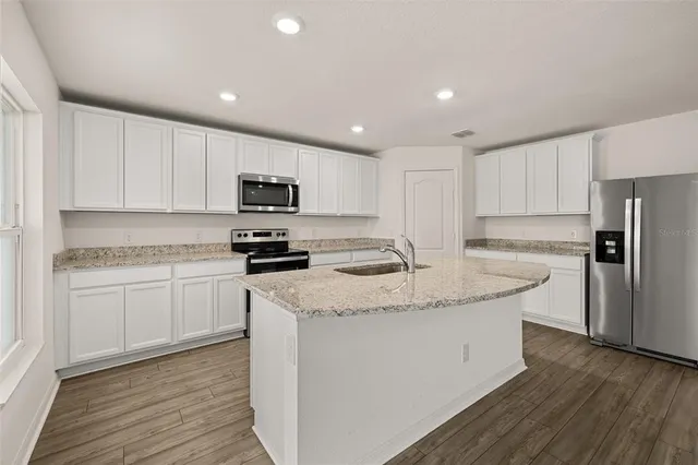a kitchen with kitchen island granite countertop a sink and a stove top oven with wooden floor