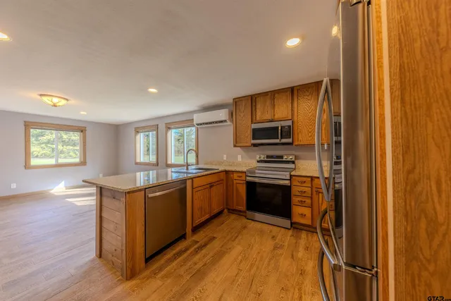 a kitchen with stainless steel appliances granite countertop a refrigerator a sink dishwasher a stove with wooden cabinets and floor