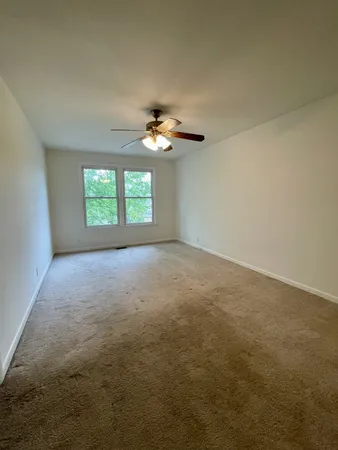an empty room with a window and a ceiling fan