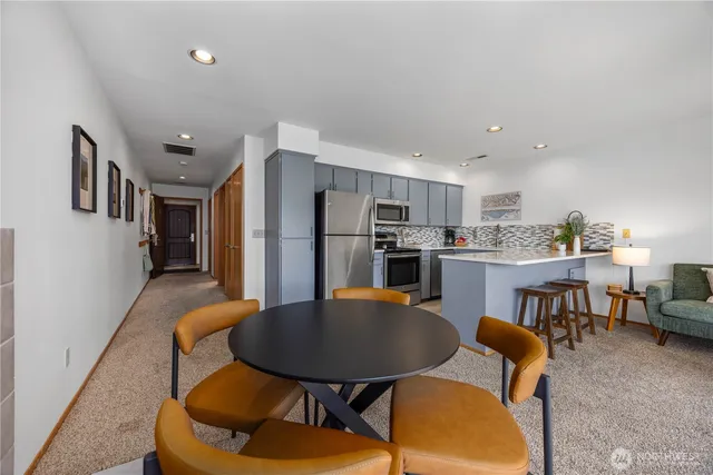 a kitchen with stainless steel appliances kitchen island granite countertop a dining table chairs and refrigerator