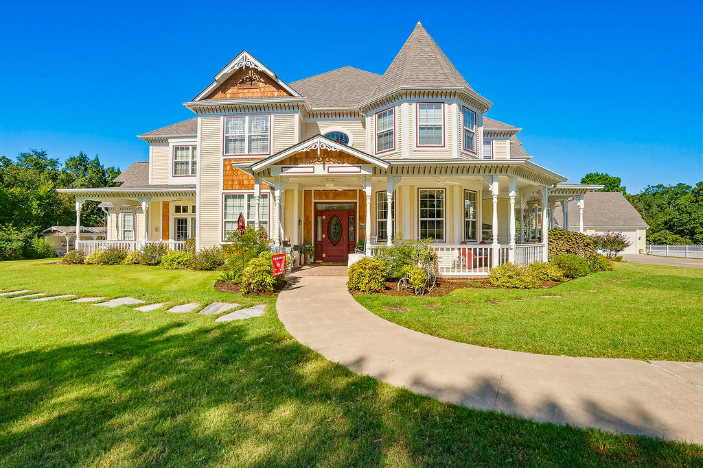 Victorian-style residence featuring a turret, wrap-around porch with detailed columns, a prominent front entry, and a paved walkway