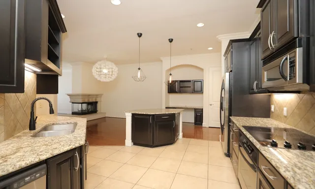 a large kitchen with stainless steel appliances granite countertop a stove a sink and a microwave