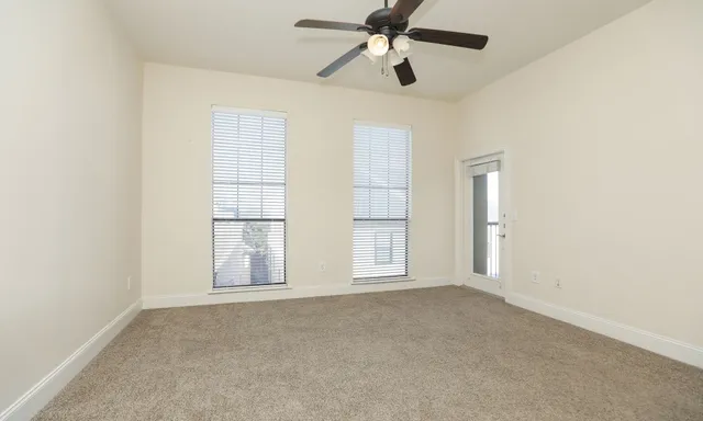 an empty room with windows and ceiling fan