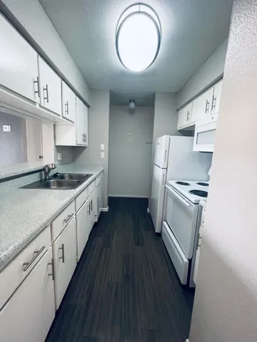 a kitchen with granite countertop a sink cabinets stainless steel appliances and a counter space