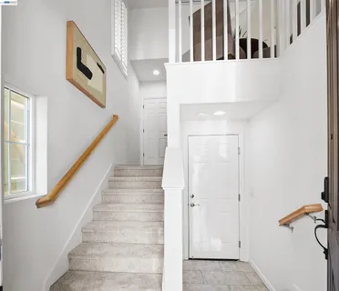 a view of staircase with lots of frames on wall and windows